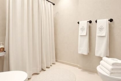 Μπάνιο με όμορφη υφασμάτινη κουρτίνα, ομοιόμορφες πετσέτες, διακοσμητικό σαπούνι και στυλάτο χαλάκι.