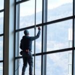 Ένα άτομο καθαρίζει παράθυρα σε ψηλό όροφο με τη χρήση τηλεσκοπικού κονταριού και καινοτόμων συσκευών καθαρισμού.