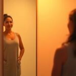 Άτομο που κοιτάζει τον εαυτό του στον καθρέφτη, αντανακλώντας αυτοαποδοχή και δύναμη.