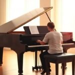 Ένα άτομο που παίζει πιάνο σε φωτεινό δωμάτιο, αποτυπώνοντας τη χαρά και τα γνωστικά οφέλη της μουσικής.