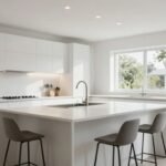 Μια λευκή κουζίνα με μοντέρνα σχεδίαση και φυσικό φωτισμό.