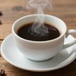 Κούπα σκέτου μαύρου καφέ με κόκκους καφέ γύρω από αυτήν.