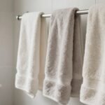 Φρέσκα πλυμένα πετσέτες κρεμασμένες σε ράφι μπάνιου με φυσικό φωτισμό
