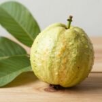 Εξωτικό φρούτο γκουάβα σε ξύλινο τραπέζι με τροπικά φύλλα.