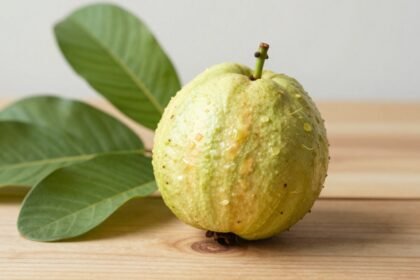 Εξωτικό φρούτο γκουάβα σε ξύλινο τραπέζι με τροπικά φύλλα.