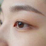 Φωτογραφία ματιού με φροντίδα και προϊόντα περιποίησης κάτω από φυσικό φως.