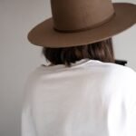 woman in white shirt wearing brown fedora hat