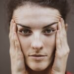 Intense close-up portrait of a woman holding her face, expressing thought.