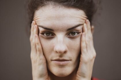 Intense close-up portrait of a woman holding her face, expressing thought.