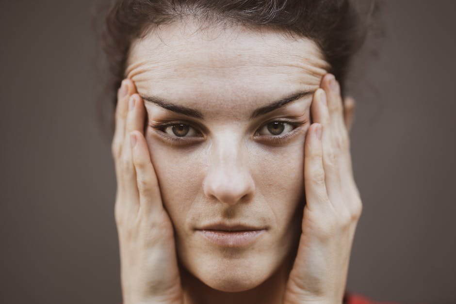 Intense close-up portrait of a woman holding her face, expressing thought.