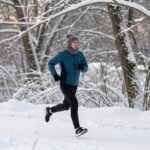 Άτομο που τρέχει στο χιόνι, ντυμένο κατάλληλα για γυμναστική σε κρύες καιρικές συνθήκες.