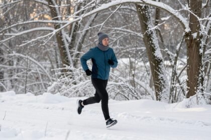 Άτομο που τρέχει στο χιόνι, ντυμένο κατάλληλα για γυμναστική σε κρύες καιρικές συνθήκες.