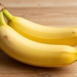 Μπανάνα τοποθετημένη σε ξύλινο τραπέζι φωτισμένη από φυσικό φως.