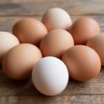 Φρέσκα αυγά σε διάφορα χρώματα σε ξύλινο τραπέζι.