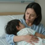 Μητέρα που κρατάει το παιδί της σε ένα νοσοκομείο με ανησυχία.