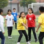 Παιδιά που παίζουν ομαδικά αθλήματα, προσφέροντας συνεργασία και κοινωνικές δεξιότητες.