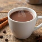 Ένα ζεστό ρόφημα σοκολάτας σε μια ξύλινη επιφάνεια, περιτριγυρισμένο από υγιεινά υλικά.