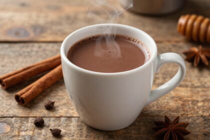 Ένα ζεστό ρόφημα σοκολάτας σε μια ξύλινη επιφάνεια, περιτριγυρισμένο από υγιεινά υλικά.