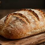 Φρέσκο ψωμί σε ξύλινη επιφάνεια, εστίαση στην υφή και τη ζεστασιά του.