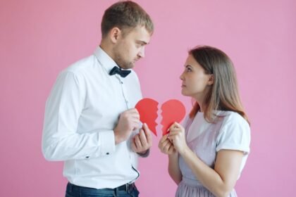 Couple holding broken heart halves on pink background