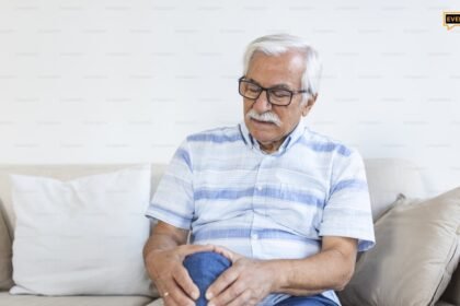 Ηλικιωμένος άνδρας στο σπίτι του που αγγίζει το πονεμένο γόνατό του