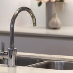 Clean sparkling stainless steel kitchen sink with modern faucet