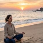 Person meditating on a beach at sunset