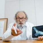 Senior doctor showing patient's X-ray on a tablet during telehealth consultation.