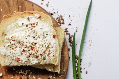 Top view of bread slices with cream cheese and spices on a wooden board.