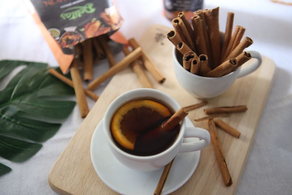 Cozy close-up of cinnamon tea with an orange slice in a white mug.